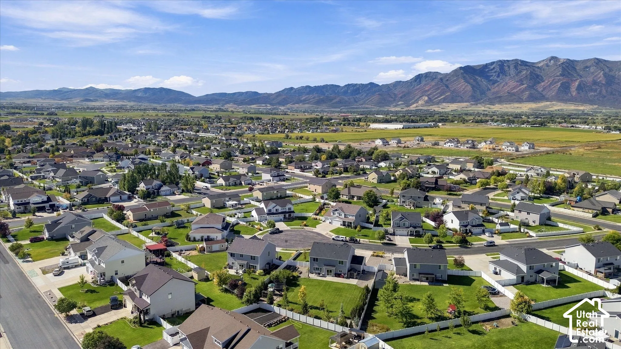 Residential development featuring detached homes, landscaped yards, paved streets, and a mountainous backdrop