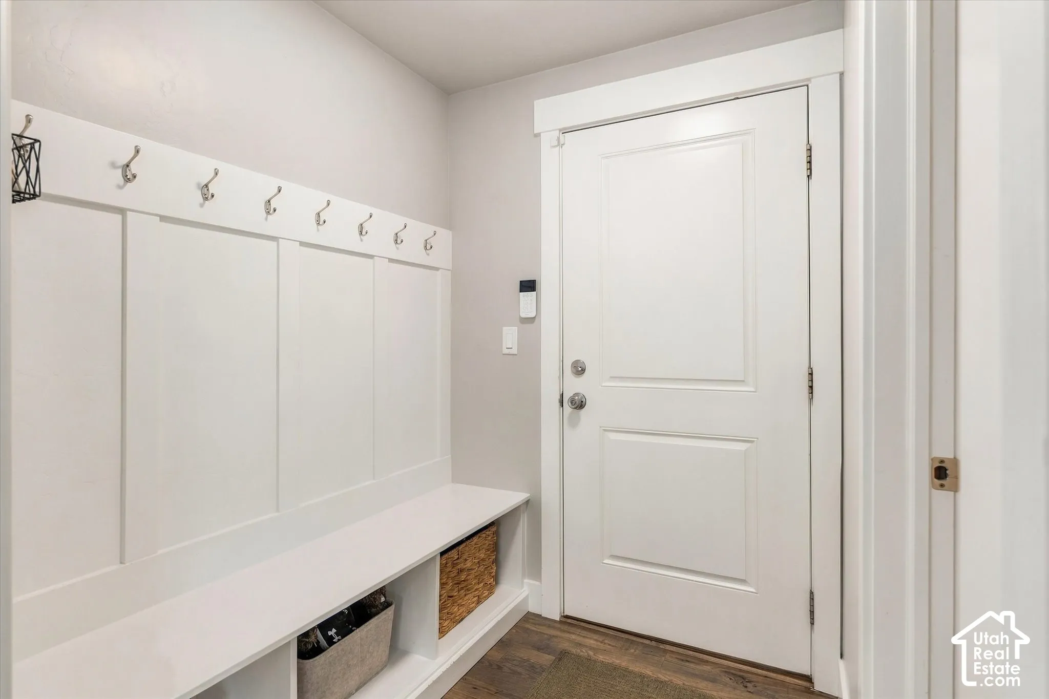 Built-in storage bench with open shelving, wall-mounted coat hooks, and durable wood-finish flooring