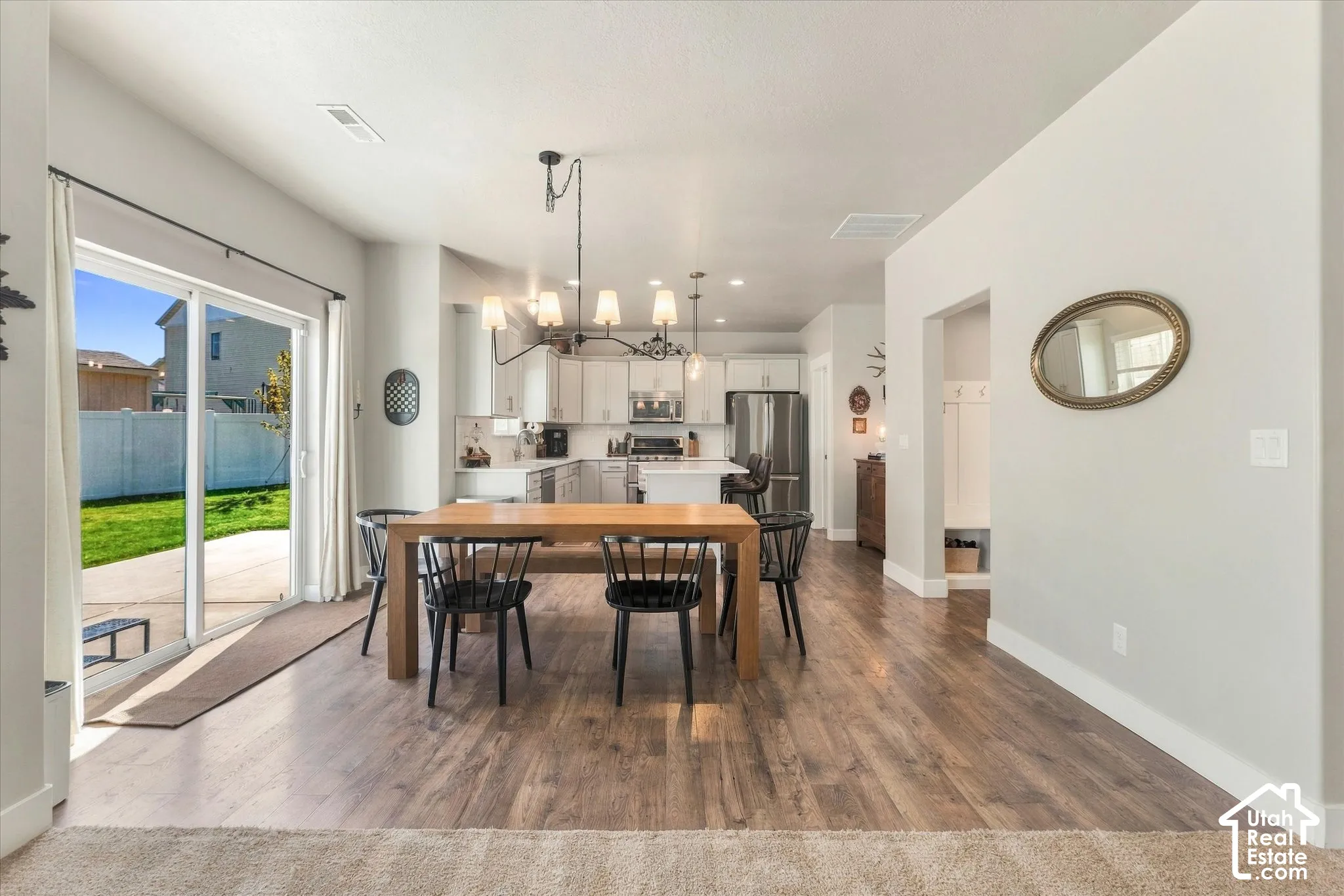 Open-concept living area with wood-finish flooring, a contemporary chandelier, and a sliding glass door to the patio