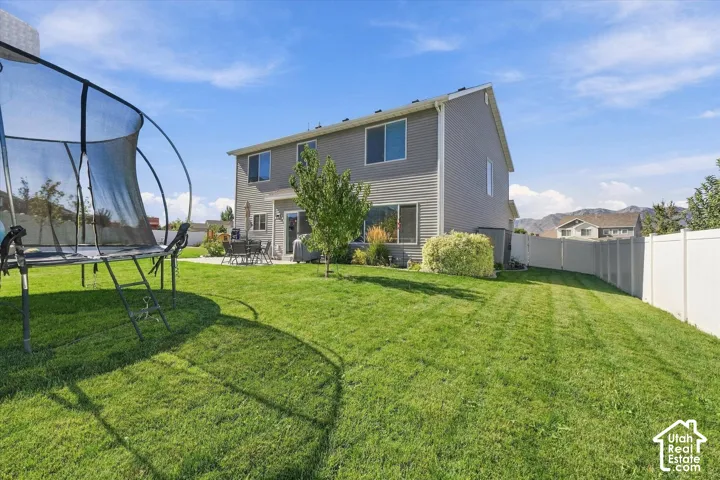 Expansive backyard featuring a manicured lawn, established landscaping, and a privacy fence
