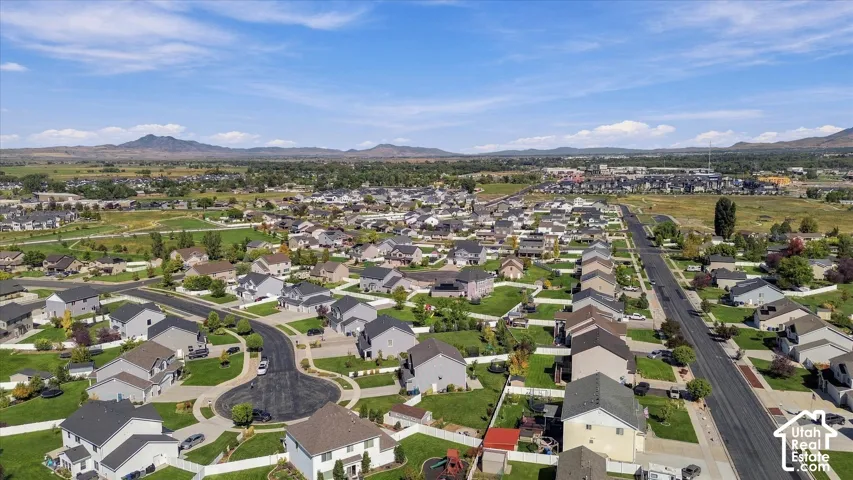 Residential development featuring multiple single-family homes with pitched roofs, expansive green spaces, and paved streets with cul-de-sacs