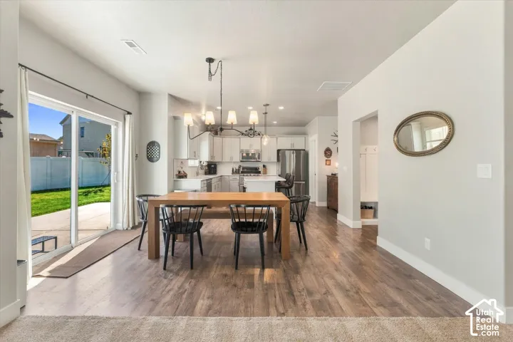 Open-concept living area with wood-finish flooring, a contemporary chandelier, and a sliding glass door to the patio