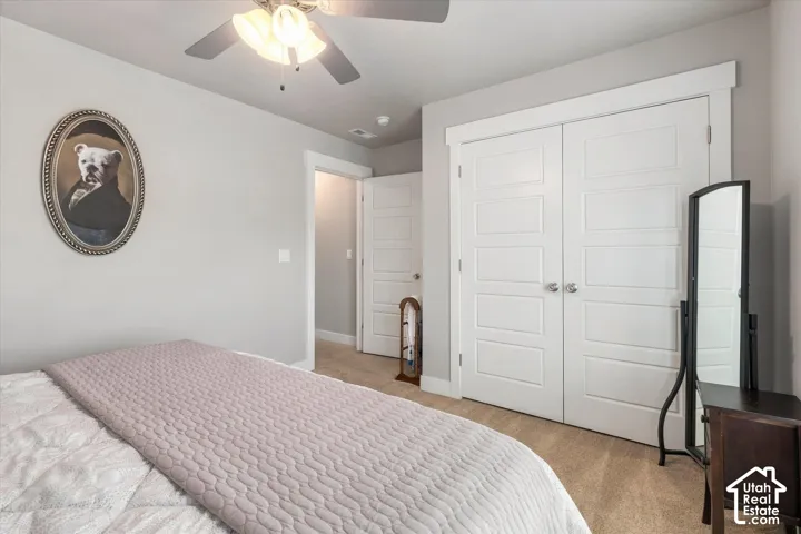 Carpeted flooring, ceiling fan with integrated lighting, white paneled doors, and light gray wall paint