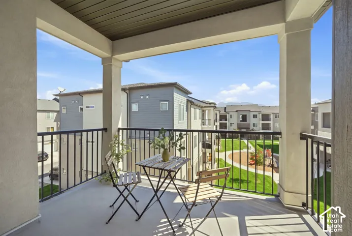 Covered balcony with a painted concrete floor, black metal railing, and slatted ceiling