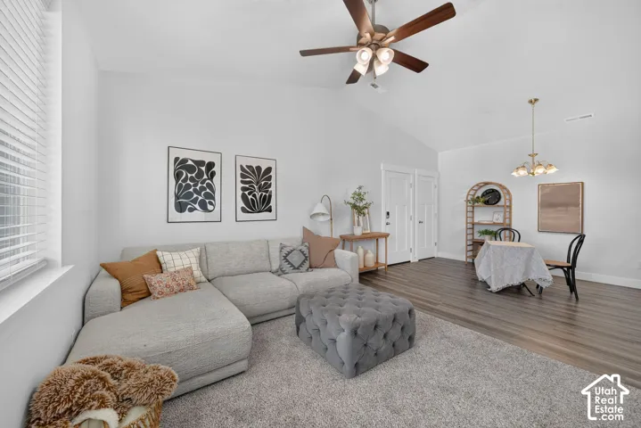 Vaulted ceiling with a ceiling fan, wood-finish flooring, and a window with blinds