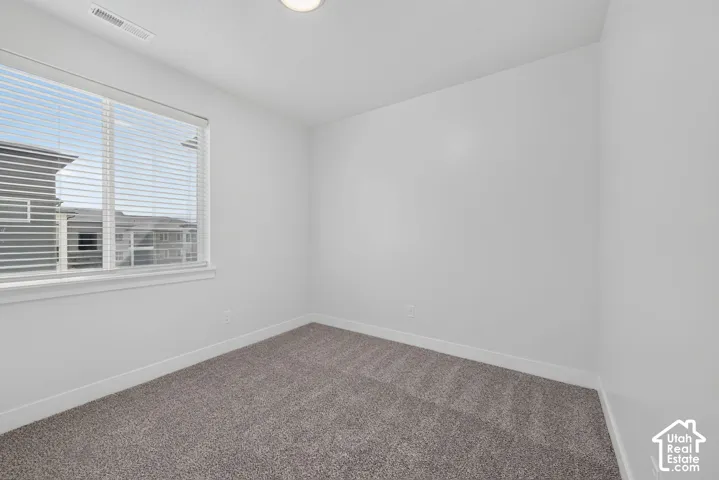 Neutral wall tones, gray carpeting, and a window with blinds
