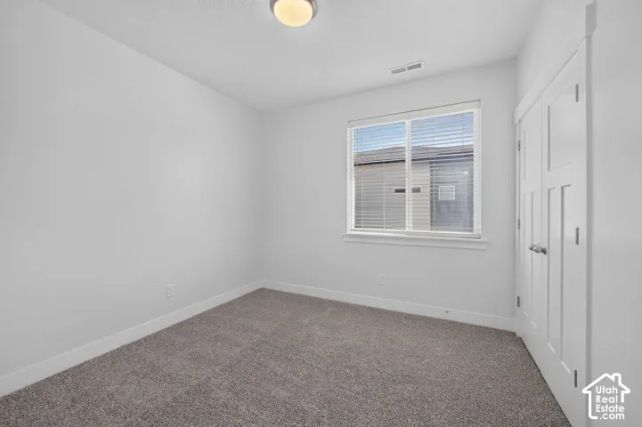 Soft gray carpet, white walls, and a window with blinds