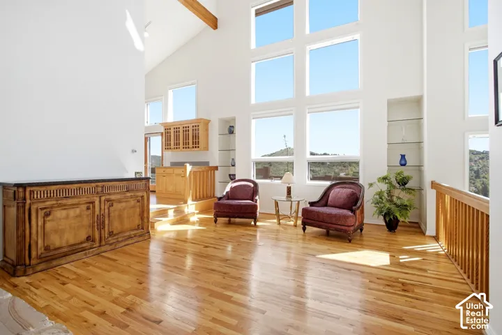 Hardwood flooring, vaulted ceilings, expansive window wall, built-in shelving, and wood-finish cabinetry