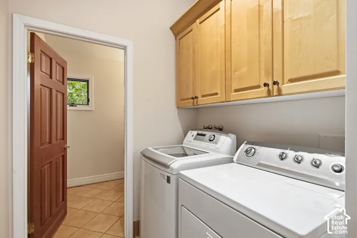Laundry area with light wood-finish cabinetry, tile flooring, and a paneled wood door