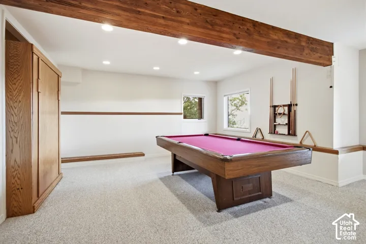 Exposed wood beam, recessed lighting, built-in wooden cabinetry, light-colored carpeting, and natural light from multiple windows