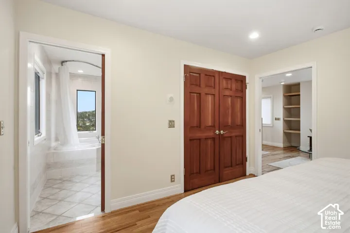 Hardwood flooring, recessed lighting, double-panel doors, built-in shelving, and a jetted tub