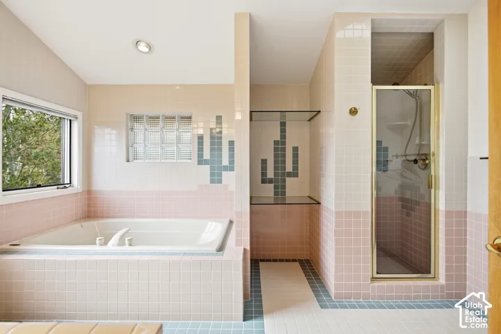 Soaking tub with tiled surround, glass block window, recessed ceiling lighting, and a separate enclosed shower with a glass door