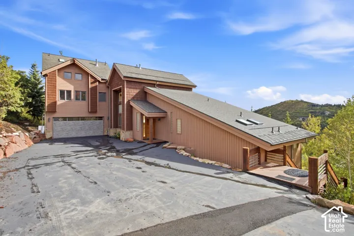 Multi-level exterior with a prominent attached garage, an extended driveway, and a sloped roofline featuring skylights