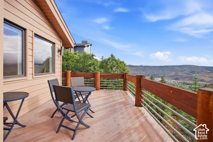 Expansive exterior deck featuring a wooden railing with horizontal metal balusters, natural wood siding, and recessed windows