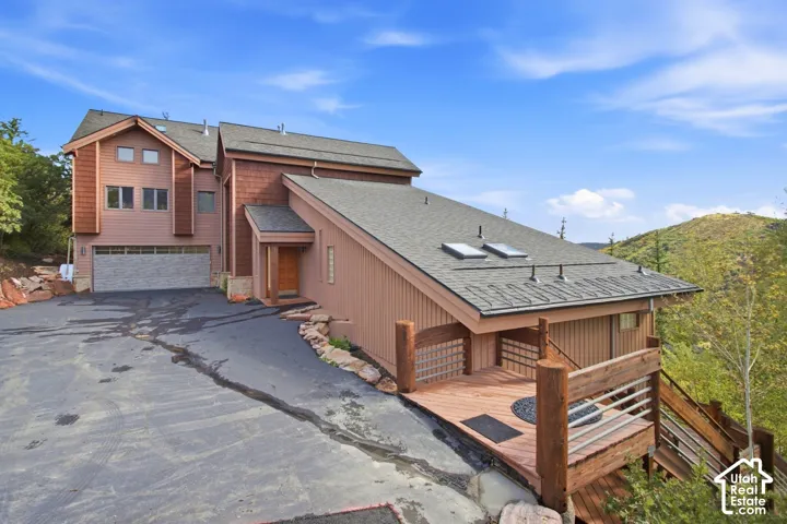 Multi-level dwelling with a two-car garage, wood siding, and an expansive outdoor deck