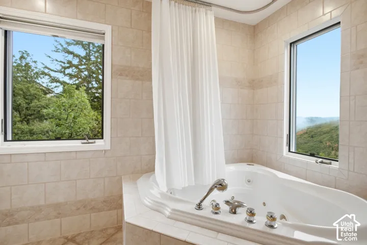 Built-in jetted tub with polished chrome fixtures, surrounded by neutral-toned tiled walls