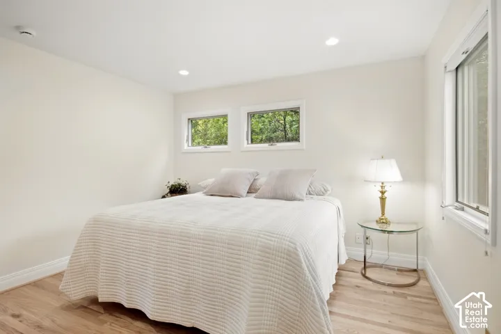Wood-finish flooring, recessed lighting, and multiple windows with white trim