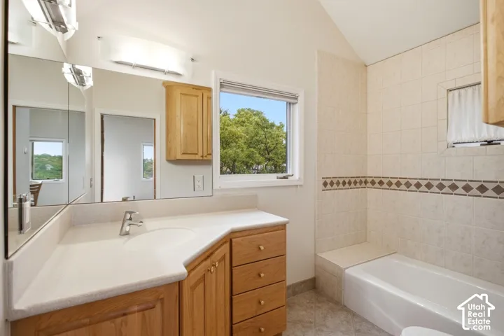 Integrated vanity with light-toned countertop, wood-finish cabinetry, and single basin sink