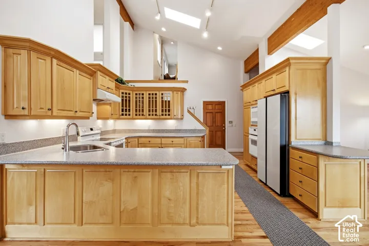 Kitchen featuring wood-finish cabinetry, granite-style countertops, stainless steel appliances, and skylights