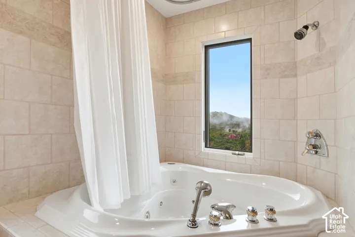 Tile surround featuring a built-in jetted tub, wall-mounted shower head, and an operable window