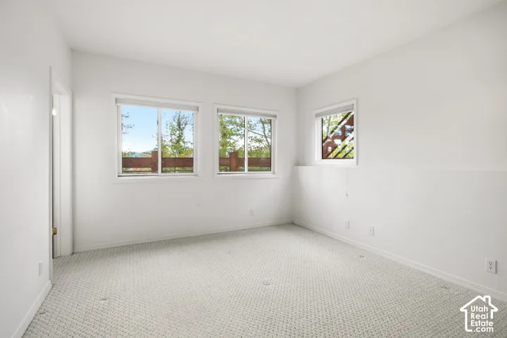 Light-filled room featuring multiple windows, white walls, and neutral carpeting