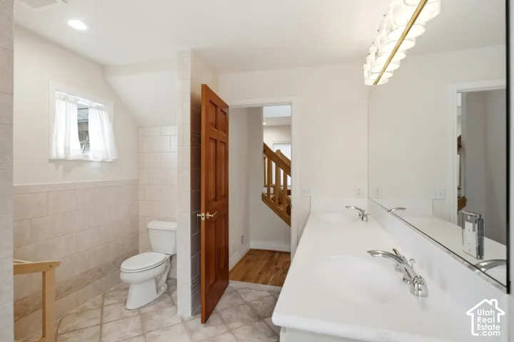 Bathroom featuring a dual-sink vanity, integrated countertop, expansive mirror, and recessed lighting