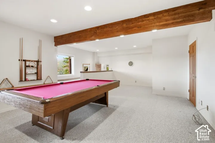 Spacious entertainment area with recessed lighting, exposed wood beam, large windows, and light-toned carpeting