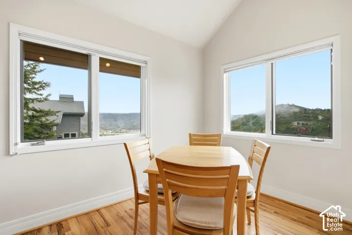 Vaulted ceiling room with wood-finish flooring and multiple windows