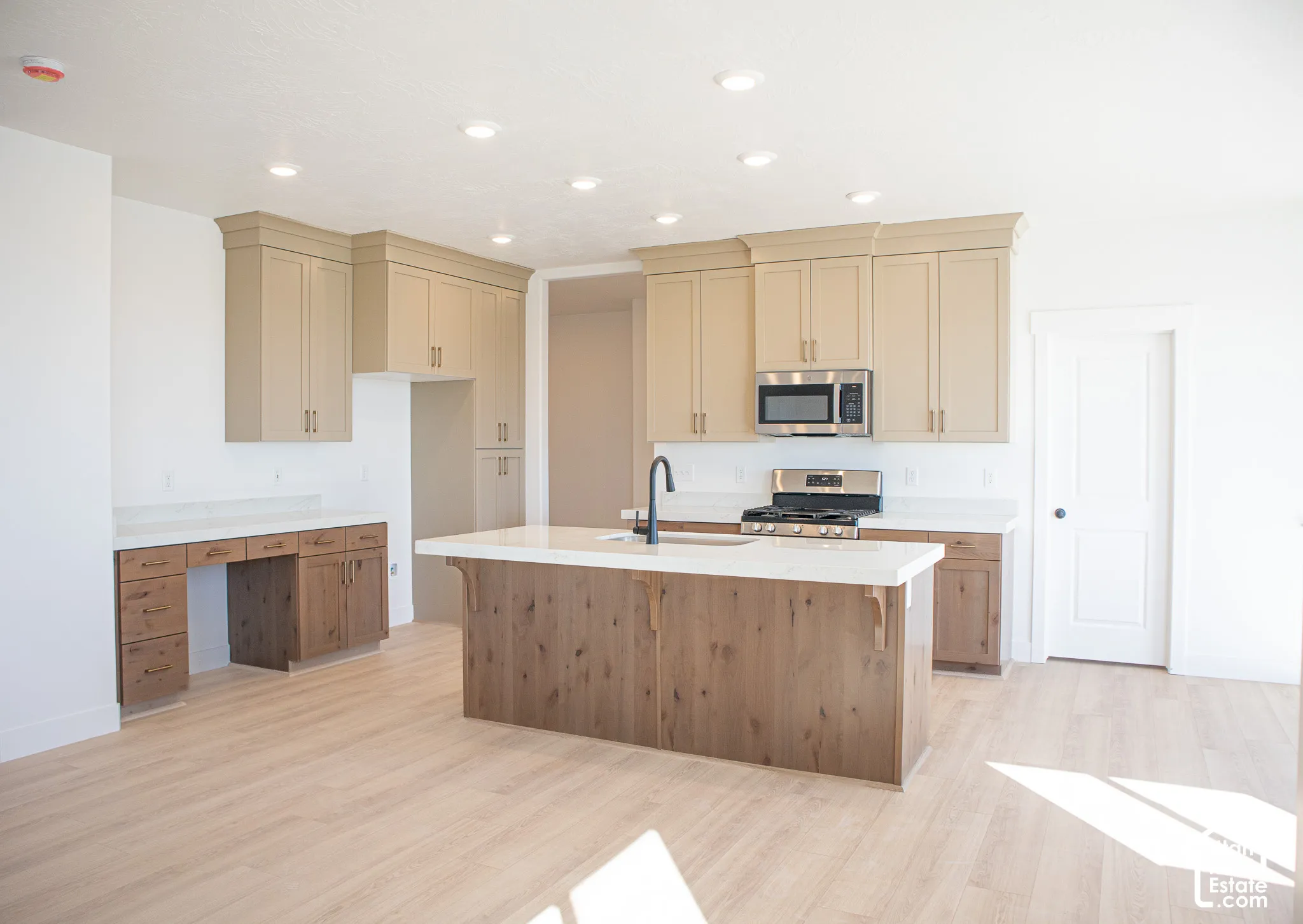 Terrific kitchen with ceiling-height, painted wood uppers; stained wood lower cabinets and island, quartz slab countertops, built-in desk, gas range, dishwasher, microwave and disposal adjacent to large dining area.