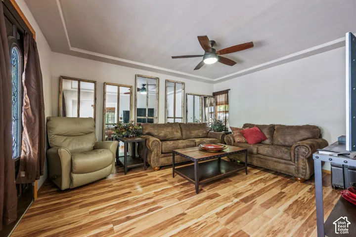 Wood-finish flooring, tray ceiling, and a ceiling fan with integrated lighting
