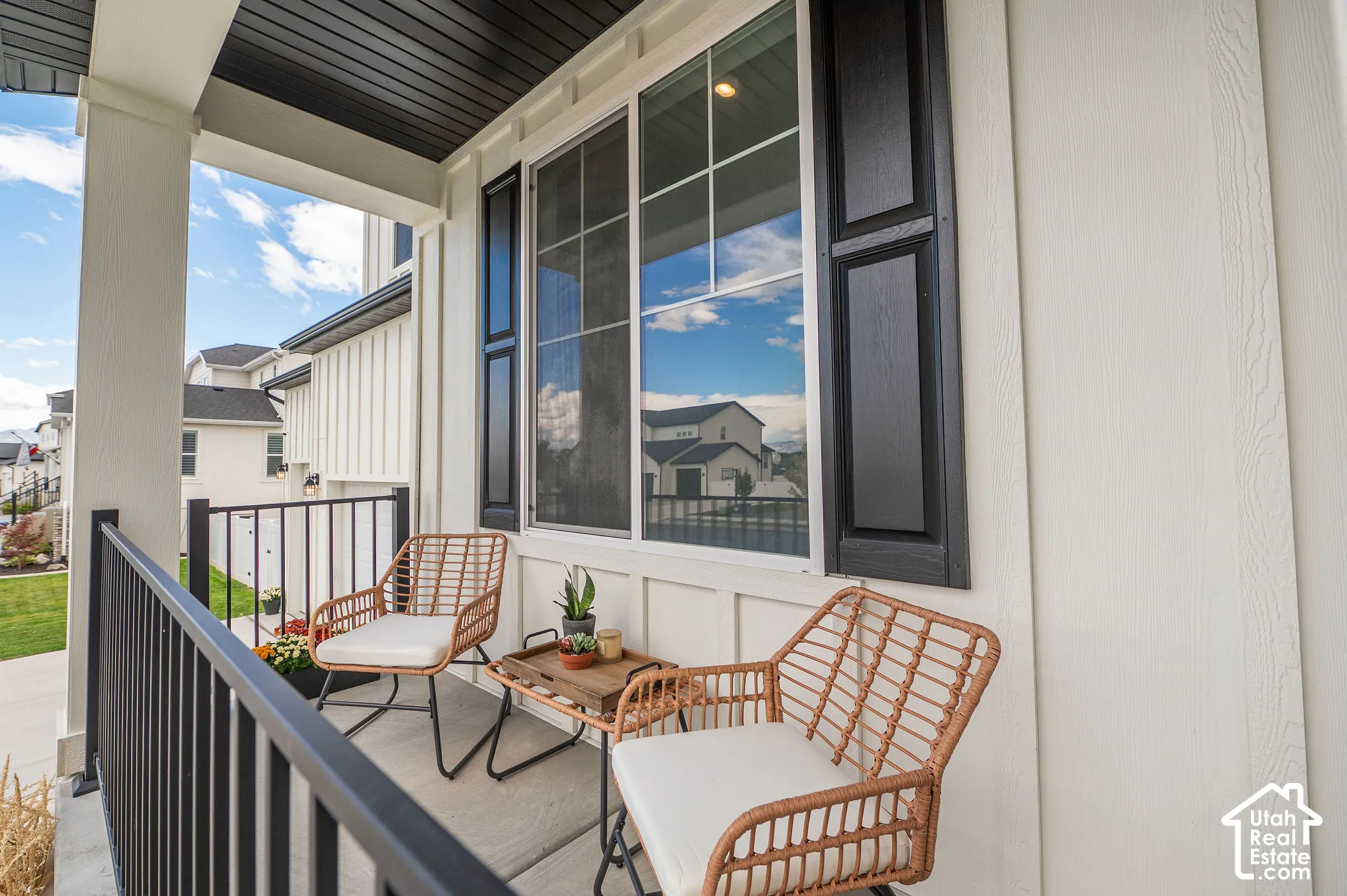 Front porch with a dark ceiling, white siding, and a black railing