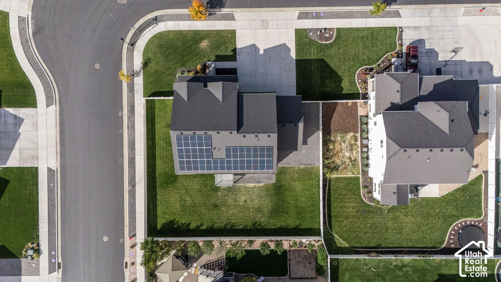 Gabled roofline with solar panel array, attached garage, concrete driveway, and manicured landscaping