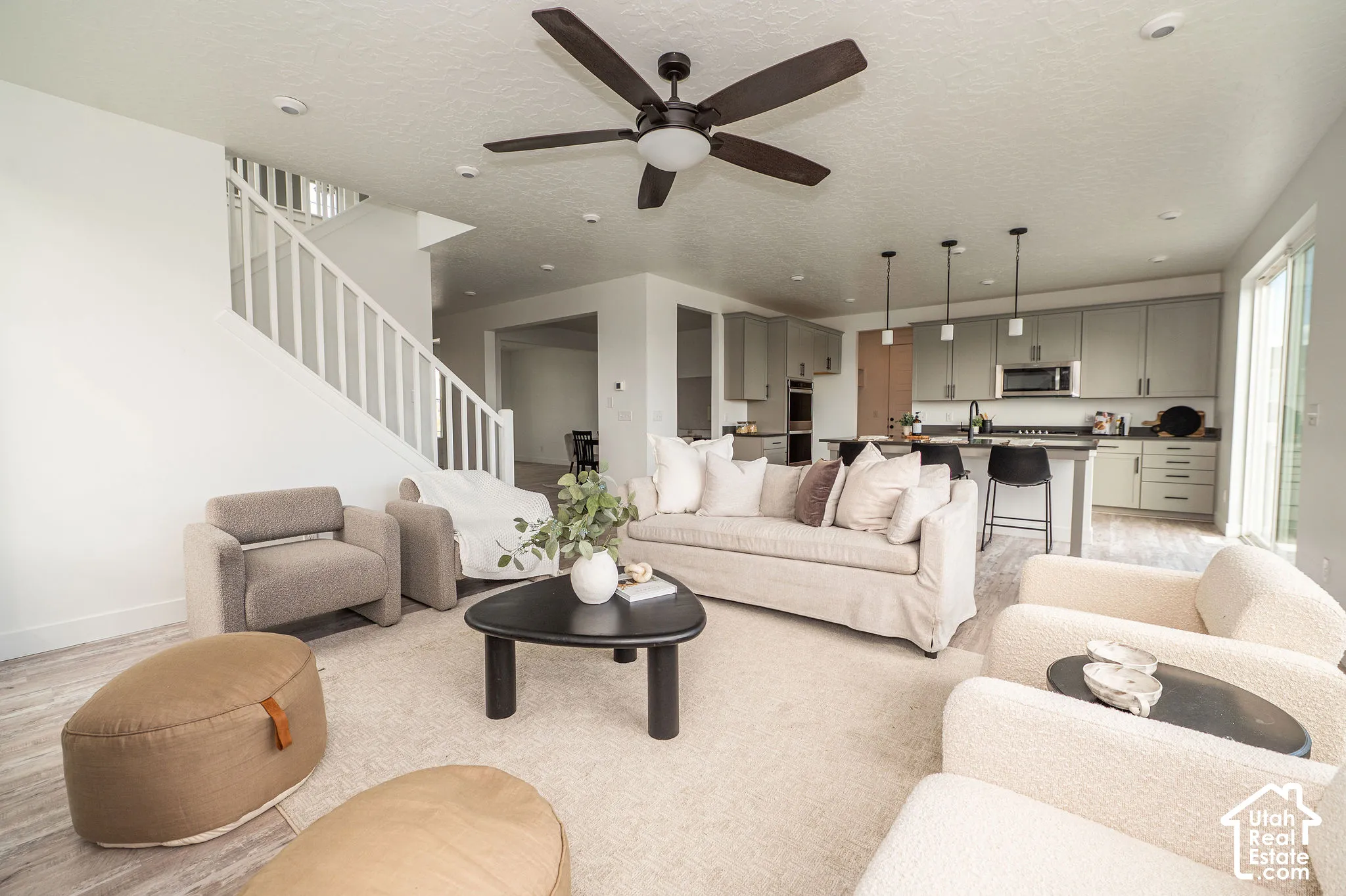 Open-concept living space with wood-finish flooring, a contemporary ceiling fan, and recessed lighting