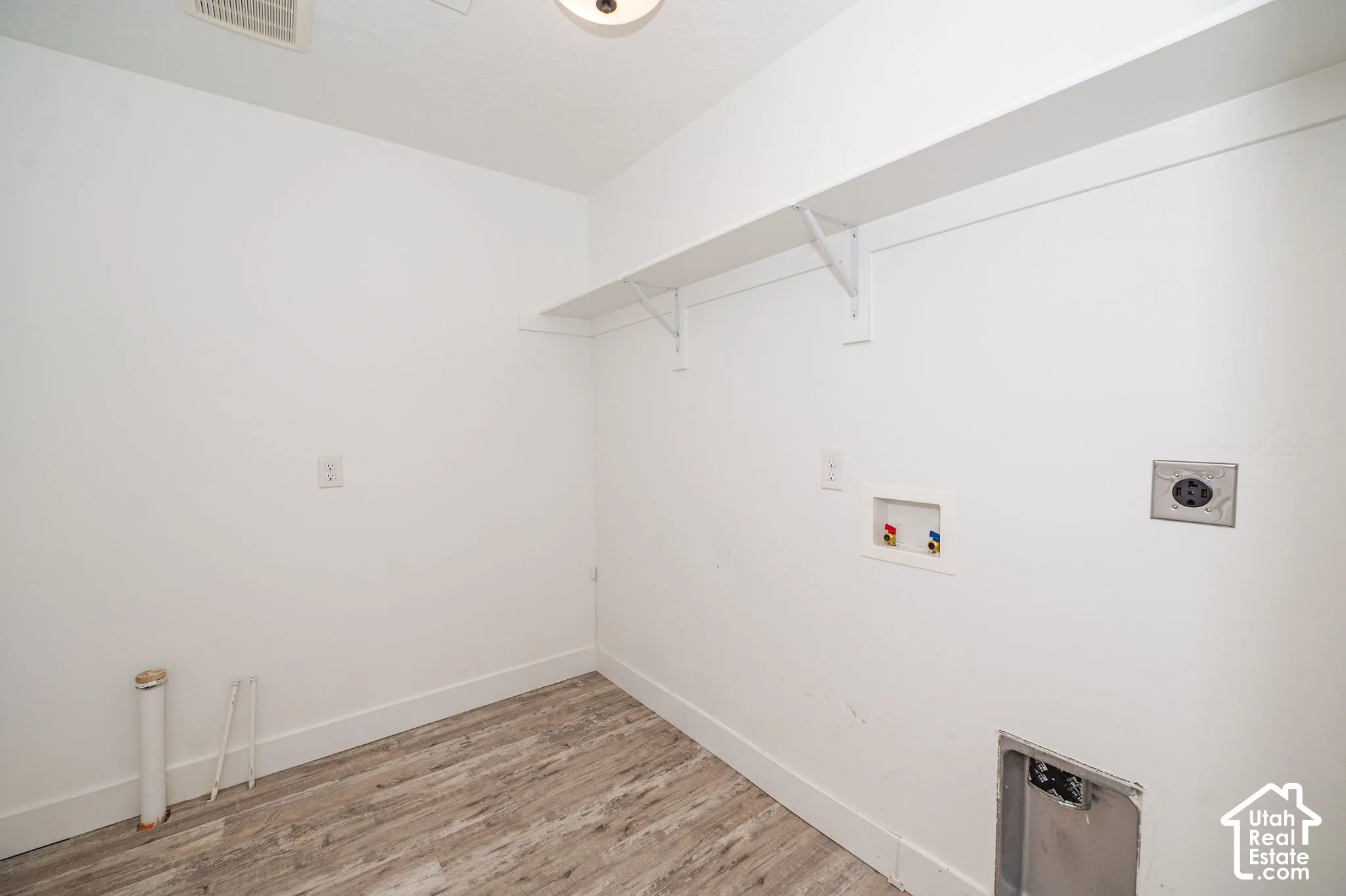 Laundry utility space with wood-finish flooring and built-in shelving