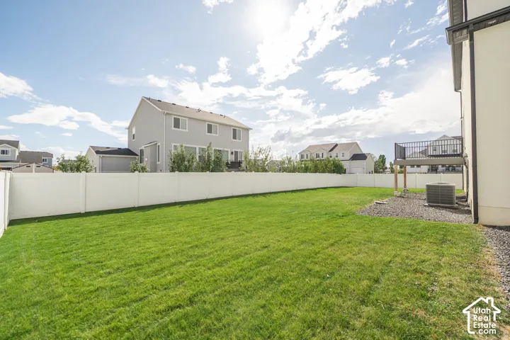 Expansive grassy lawn with a white privacy fence and a rear deck featuring black metal railings