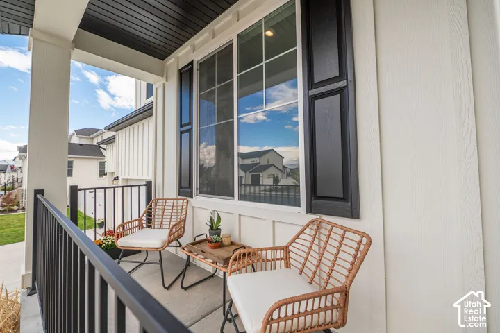 Front porch with a dark ceiling, white siding, and a black railing