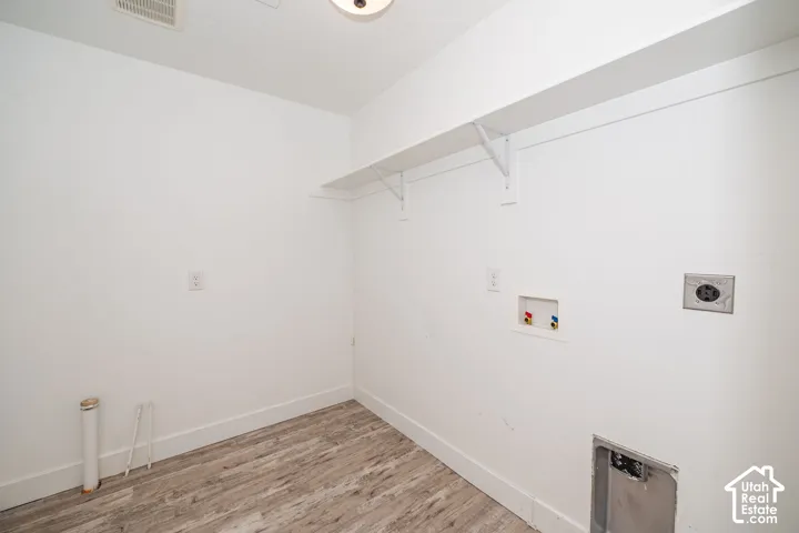 Laundry utility space with wood-finish flooring and built-in shelving