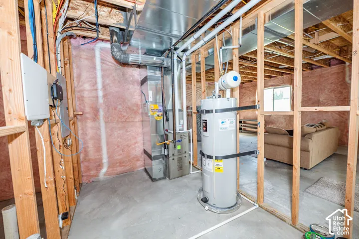 Unfinished basement area featuring a water heater, furnace,