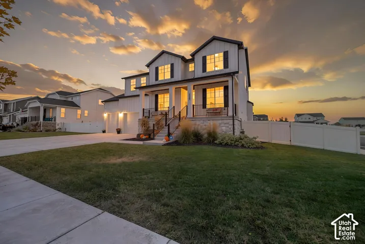 Two-story residence featuring a covered front porch, stone accents, and a two-car garage