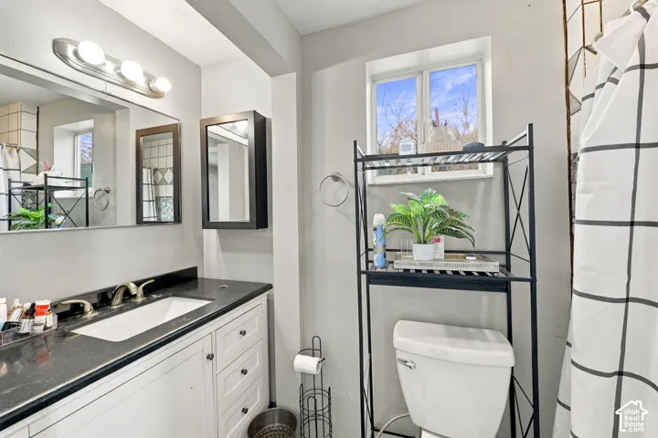 Bathroom featuring a single vanity with a dark countertop, white cabinetry, and a rectangular undermount sink