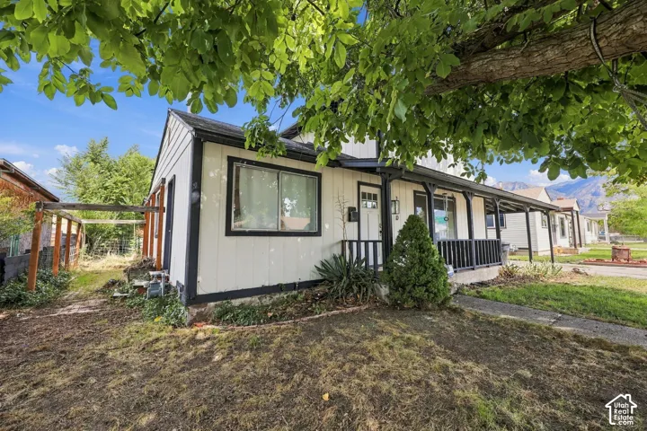 White exterior siding with dark trim, covered front porch, and a side-yard trellis structure