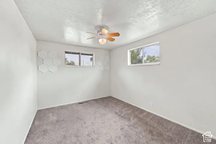 Neutral wall finishes, textured ceiling, and a ceiling fan with light fixture