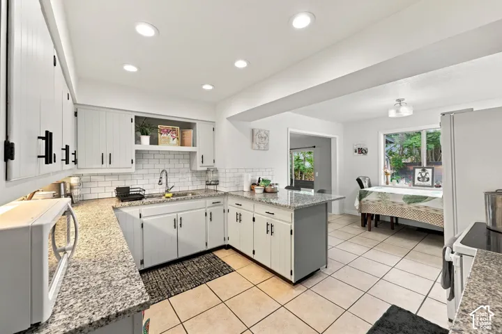 Kitchen featuring light-finish cabinetry with black hardware, stone-finish countertops, subway tile backsplash, and recessed lighting