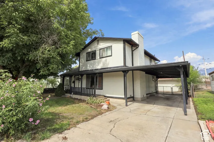 Two-story residence featuring a covered front porch, an attached carport, and a prominent chimney