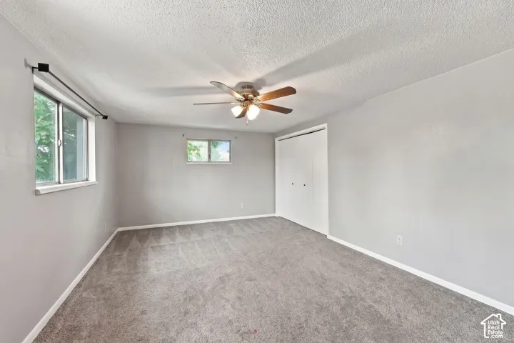 Primary Bedroom. Carpeted flooring, ceiling fan with integrated lighting, multiple windows, and a built-in closet with bifold doors