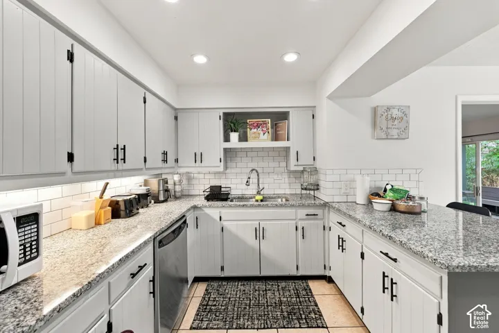 Kitchen featuring light-toned cabinetry with dark hardware, speckled countertops, a subway tile backsplash, and recessed lighting