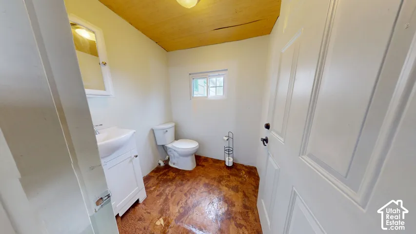 White paneled door, wood-finish ceiling, mounted light fixture, white vanity with integrated sink, and white framed mirror