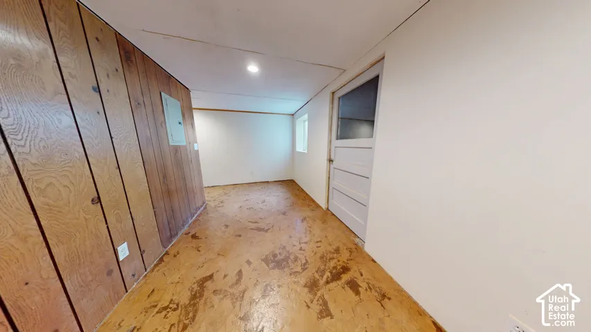 Recessed lighting, wood paneling, white painted walls, and a paneled door with a frosted glass insert