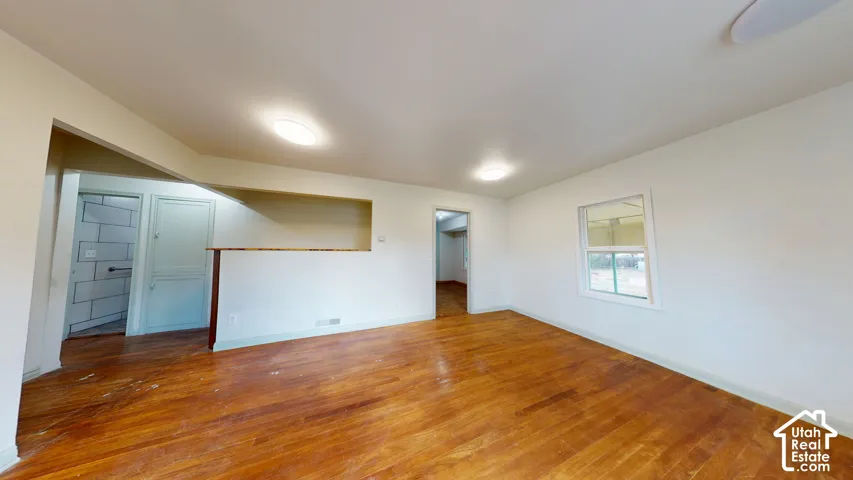 Hardwood flooring, painted walls, ceiling-mounted light fixtures, and a pass-through opening