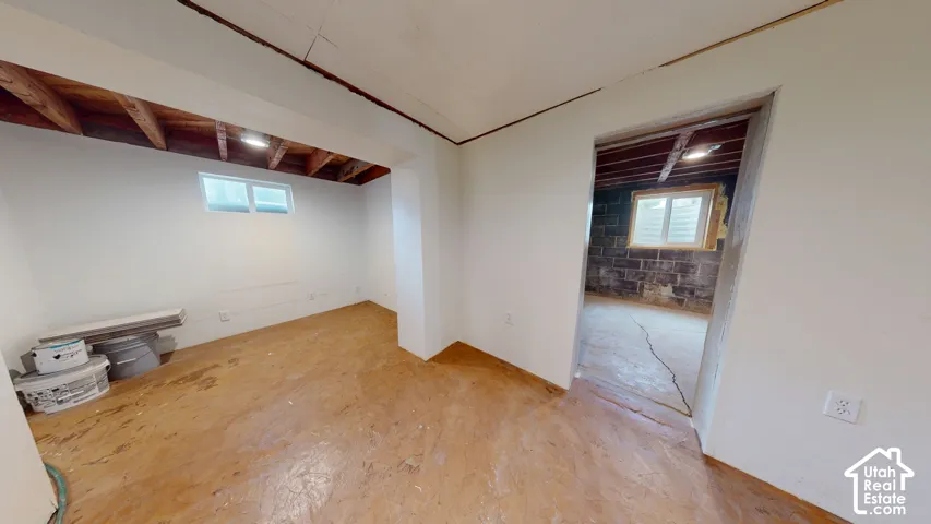 Unfinished interior space with exposed ceiling joists, white painted walls, and an egress window